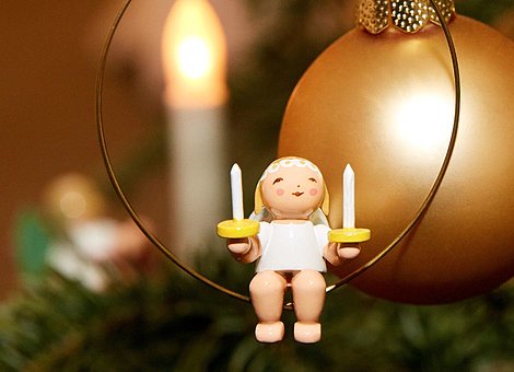 [Translate to Englisch (US):] Holzfigur "Margeritenengel im Ring" vor goldener Christbaumkugel