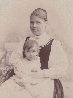 [Translate to Englisch (US):] Historische Schwarz-Weiß-Fotografie. Olly als Baby auf dem Schoß ihrer Mutter.
